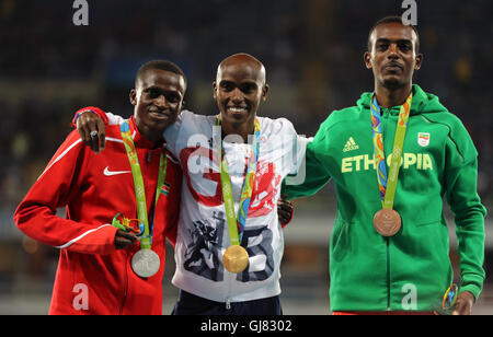 Der Brite Mo Farah (Zentrum mit seiner Goldmedaille nach den Männern 10.000-Meter-Finale mit Silber und Bronze-Medaillengewinner Paul Kipngetich Tanui von Kenia (links) und Tamirat Tola von Äthiopien (rechts) im Olympia-Stadion am achten Tag der Olympischen Spiele in Rio, Brasilien. Stockfoto