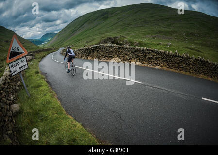 Radfahrer absteigen Kirkstone Pass hinunter in Ullswater, Cumbria, UK. Stockfoto