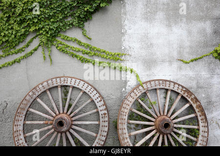 Hölzernes Rad auf dem Hintergrund einer alten Backstein-Mauer Stockfoto