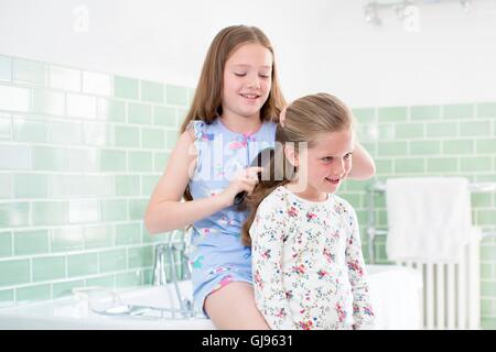 EIGENTUM FREIGEGEBEN. -MODELL VERÖFFENTLICHT. Große Schwester, kleine Schwester Haare im Bad putzen. Stockfoto