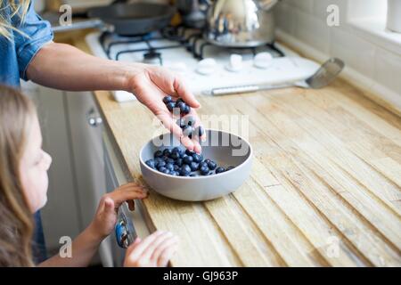 EIGENTUM FREIGEGEBEN. -MODELL VERÖFFENTLICHT. Mädchen betrachten Schüssel mit frischen Heidelbeeren. Stockfoto
