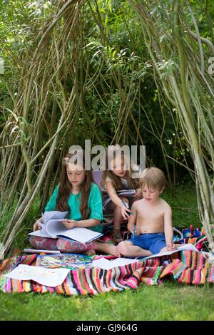 EIGENTUM FREIGEGEBEN. -MODELL VERÖFFENTLICHT. Kinder spielen in einer Höhle im Garten. Stockfoto