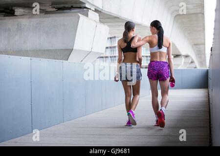 -MODELL VERÖFFENTLICHT. Zwei junge Frauen im Sport tragen zu Fuß entfernt. Stockfoto