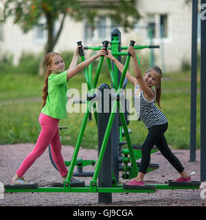 Kinder Mädchen üben Gymnastik auf der öffentlichen Sportgeräte im Freien. Stockfoto