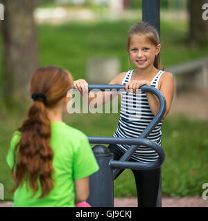 Kinder Mädchen üben Gymnastik auf der öffentlichen Sportgeräte im Freien. Stockfoto