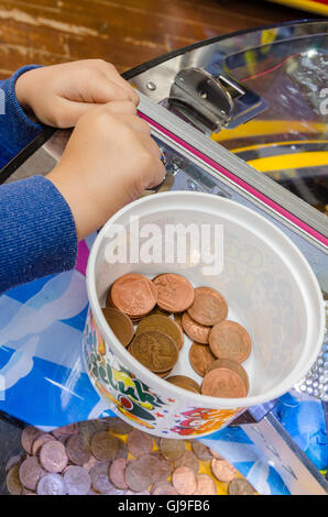 Ein kleiner Junge spielt auf einem 2P-Spielautomaten in einer Spielhalle in einem Ferienort. Stockfoto