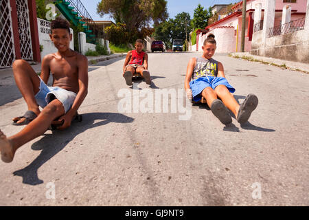 Kinder reiten hausgemachte Skateboards hinunter einen Hügel in der Gemeinde von Regla, Havanna, Kuba. Stockfoto