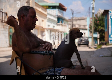 Ein Mann mit seinen haarlosen Hund sitzt auf seinem Schoß in der Gemeinde von Regla, Havanna, Kuba. Stockfoto