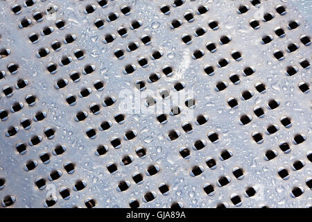 Wassertropfen auf perforierten Metall-Oberflächen-Hintergrund Stockfoto