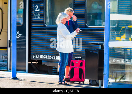 Kalmar, Schweden - 10. August 2016: Ein älteres paar stehen auf dem Bahnsteig vor einem Eisenbahnwaggon. Sie erschließen ein Stockfoto