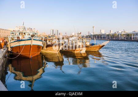 Traditionellen altmodischen hölzernen arabischen Dhaus ankern in sonnigen Dubai Creek, Deira, Dubai, Vereinigte Arabische Emirate vor dem Hintergrund der Wolkenkratzer Stockfoto