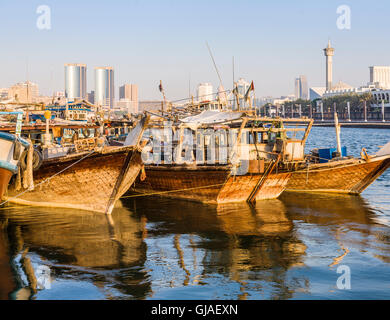 Traditionellen altmodischen hölzernen arabischen Dhaus ankern in sonnigen Dubai Creek, Deira, Dubai, Vereinigte Arabische Emirate vor dem Hintergrund der Wolkenkratzer Stockfoto