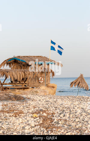 Einsame Strohhütte mit griechische Flagge auf dem Dach am Meeresstrand Stockfoto