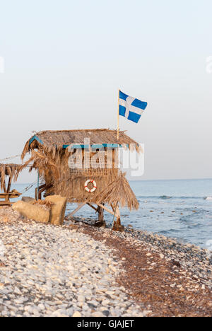 Einsame Strohhütte mit griechische Flagge auf dem Dach am Meeresstrand Stockfoto