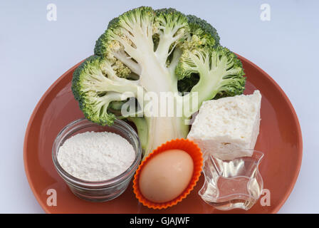 Kochen Zutaten: Frischer Brokkoli, Scharfkäse Käse, Ei, Sonnenblumenöl und Mehl auf einem braunen Teller bereit zum Kochen Closeup. Stockfoto