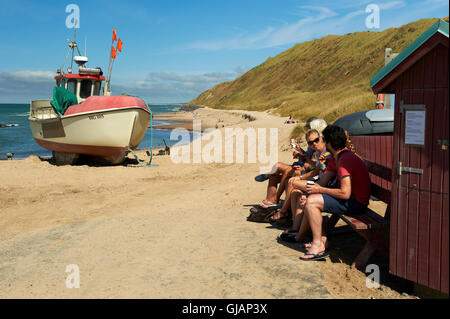 Italienische Touristen sitzen auf einer Bank, Eis essen, am Strand des Fischerdorfes Loenstrup (Lønstrup), Jütland, Dänemark Stockfoto