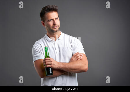 Ein hübscher junger Mann sucht verdächtig halten Sie ein Bier Stockfoto