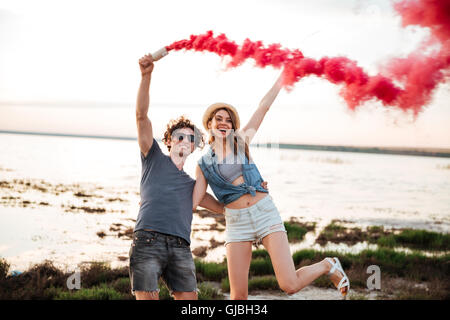 Glückliches junges Paar stehen und Spaß mit Rauch Bombe in der hand Stockfoto