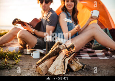 Zugeschnittenes Bild eines jungen Paares in der Liebe Braten Marshmallow am Lagerfeuer beim camping Stockfoto