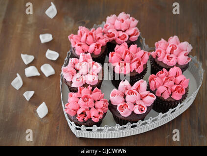 Cupcakes. Schoko Cupcakes mit rosa Vanilla buttercream rosebuds in Herzform platter Stockfoto