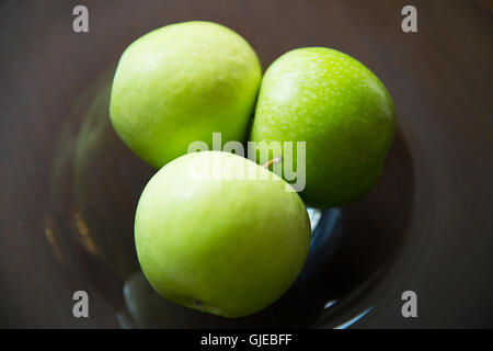 Nahaufnahme von grünen Äpfeln auf Glasplatte Stockfoto