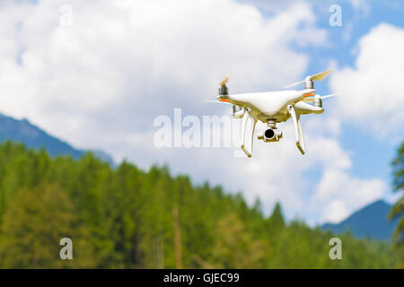Weiße Drohne Quad Copter mit hochauflösenden Digitalkamera fliegen in den blauen Himmel über den Berg Stockfoto