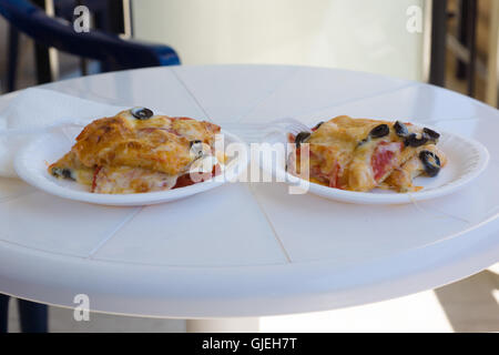 Scheiben von saftig duftenden Pizza auf einem Teller auf dem Tisch stehen Stockfoto