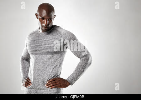 Porträt von muskulösen jungen Mann stehend mit den Händen auf den Hüften nach unten vor grauem Hintergrund. Starken afrikanischen Männermodel. Stockfoto