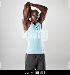 Porträt von muskulösen jungen Mann streckte Arme und Blick in die Kamera. Afrikanische Männermodel Ausübung auf grauem Hintergrund. Stockfoto