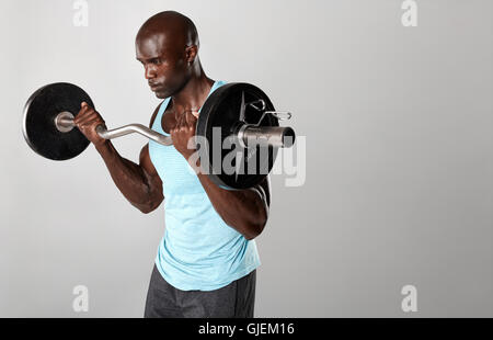 Porträt von Fit Jüngling anhebende Langhantel vor grauem Hintergrund. Jungen muskulösen Mann Training mit Gewichten. Stockfoto