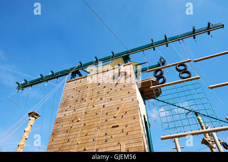 Junges Mädchen erreichen der Spitze der eine Outdoor-Kletterwand am Conkers Anziehungspunkt innerhalb der National Forest Moira Derbyshire UK Stockfoto