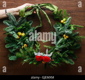 Blumenkranz Weihnachtsdekoration mit Kugeln, rote Schleife, Holly und Winter Grün über Eiche Hintergrund. Stockfoto