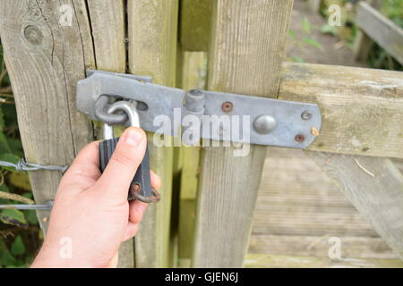 Hand, die Eisen-Sperre auf ein hölzernes Tor Stockfoto