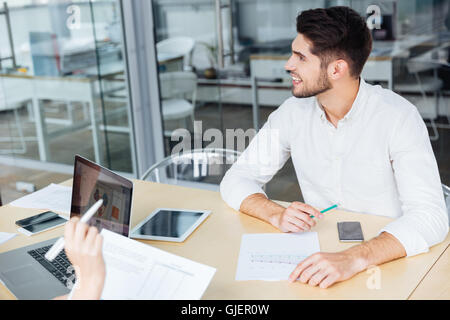 Fröhliche junge Unternehmer sitzen und arbeiten auf Business-Meeting im Konferenzraum Stockfoto