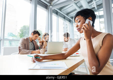 Schwere jungen afrikanischen Geschäftsfrau arbeiten und reden über Handy auf Business-meeting Stockfoto