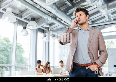 Schwere hübscher junger Geschäftsmann stehend und telefonieren mit Handy im Büro Stockfoto