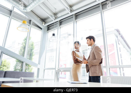 Zwei junge Geschäftsleute stehen und reden im Büro Stockfoto