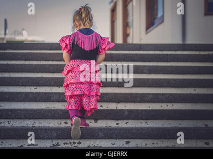 Vier Jahre alten Mädchen gekleidet in rosa Salsa-Kostüm steigen die Treppe in der Stadt Stockfoto