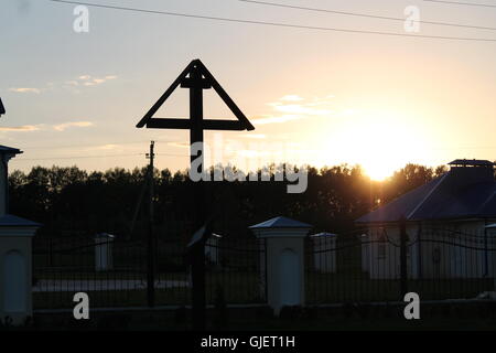 Retro-Stil orthodoxen Holzkreuz unter Dreieck Dach Aufenthalt in Strahlen der Sommer Sonnenuntergang Stockfoto