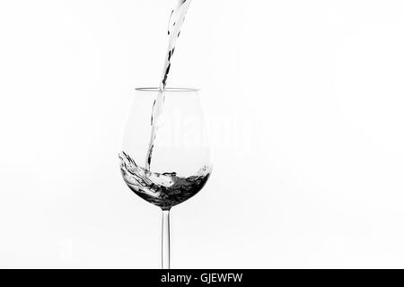 Wein-Spritzer in ein Glas Wein in schwarz / weiß Stockfoto