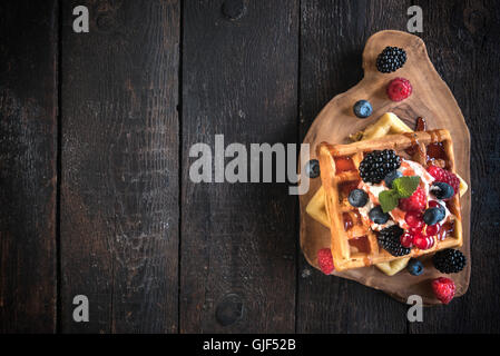 Traditionellen belgischen Waffeln mit Beeren und Eis auf hölzernen Hintergrund, Tiefenschärfe und Leerzeichen Stockfoto