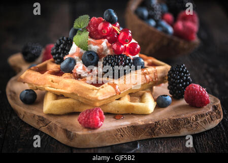 Belgien-Waffeln auf Holzbrett mit Beeren und Eis am oberen, selektiven Fokus Stockfoto