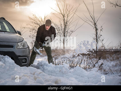 Man gräbt stecken im Schnee Auto Stockfoto