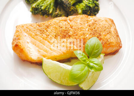 Gebackener Lachs mit frischem Basilikum und Limettenscheiben serviert Gourmet Stockfoto