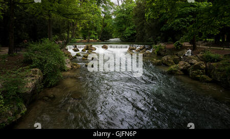 Eine Person liest ein Buch entlang des Flusses Eisbach im englischen Garten in München im Sommer. Stockfoto