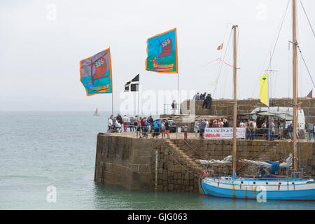 Meer Salze & Segel, farbigen Fahnen im Wind, Mousehole Hafen, Cornwall, UK. Stockfoto