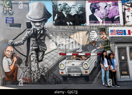Touristen posieren durch das Wandbild auf der East Side Gallery Store, Friedrichshain, Berlin, Deutschland. Stockfoto