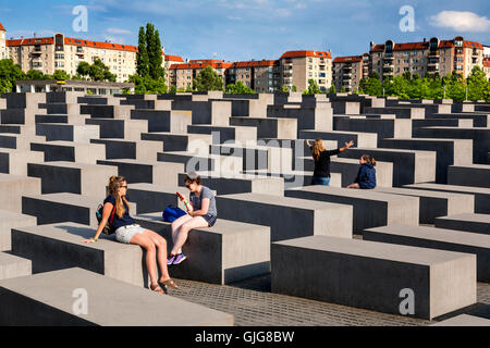 Touristen sitzen auf die Betonsteine von das Holocaust-Mahnmal für die ermordeten Juden Europas, Berlin, Deutschland. Stockfoto