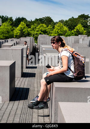 Touristen sitzen auf die Betonsteine von das Holocaust-Mahnmal für die ermordeten Juden Europas, Berlin, Deutschland. Stockfoto