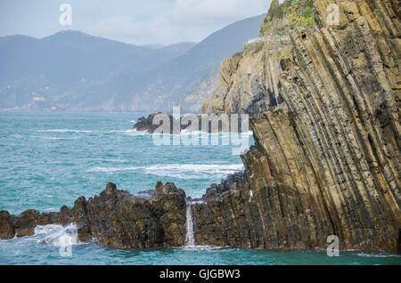 Wellen brechen über Klippen in Riomaggiore, Ligurien, Cinque Terre, Italien Stockfoto